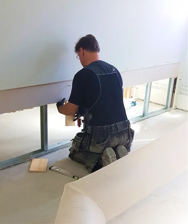 A person is repairing a wood wall